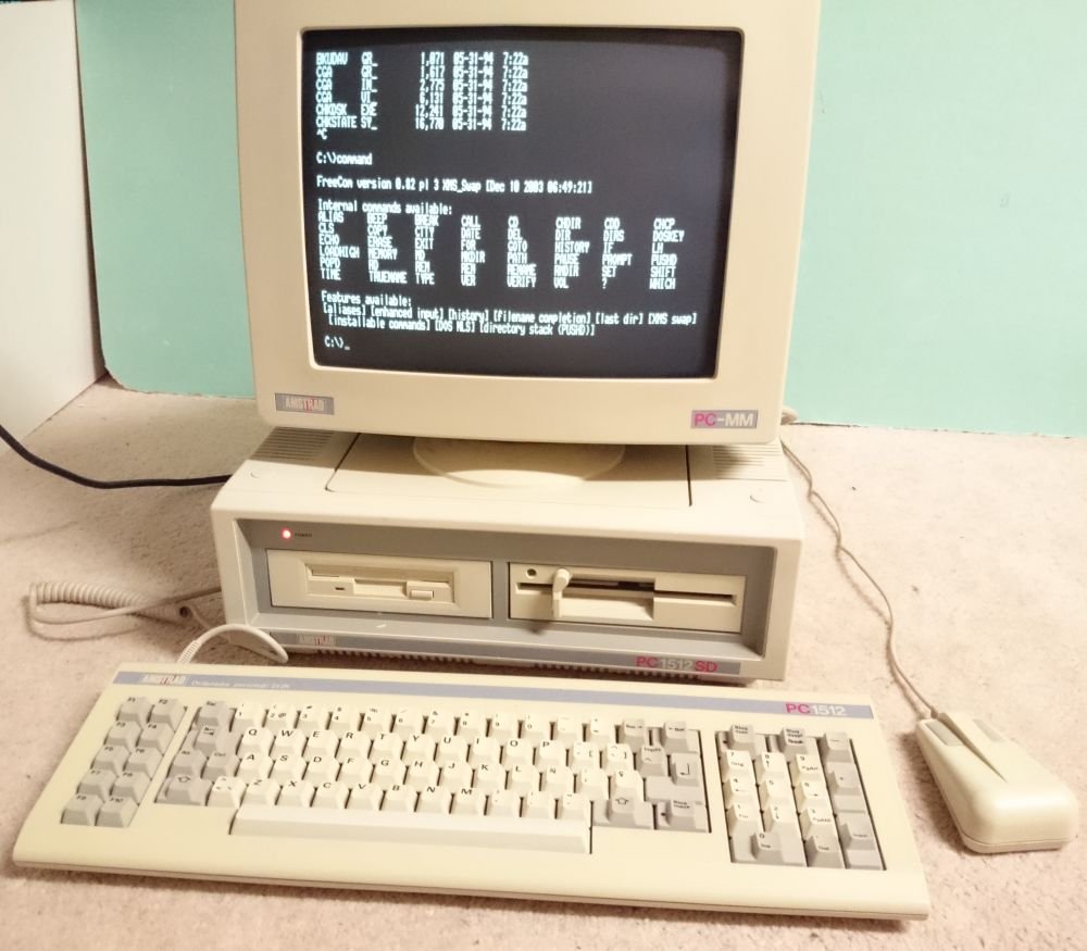 Amstrad PC-1512 avec écran affichant l'invite FreeCom, clavier AZERTY, souris et double lecteur de disquettes