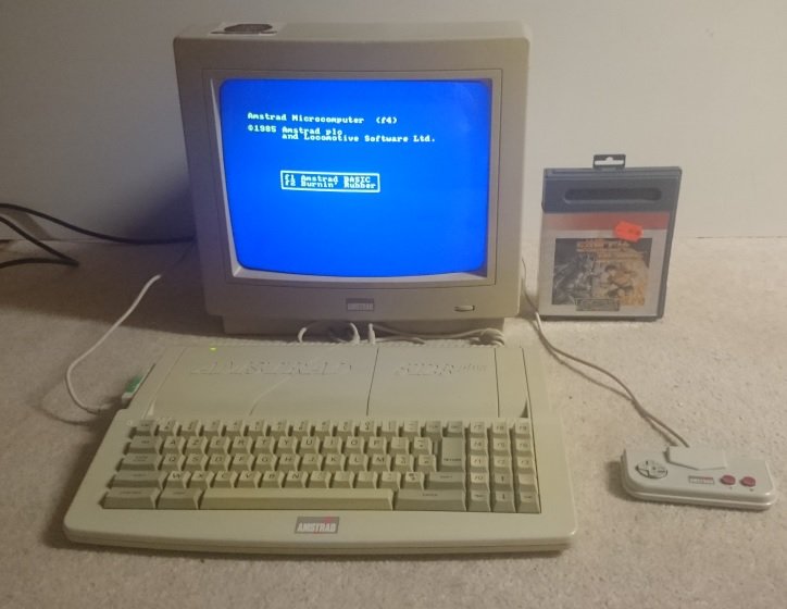 Amstrad 6128 Plus allumé, écran affichant l'invite BASIC, avec cartouche de jeu et manette d'origine
