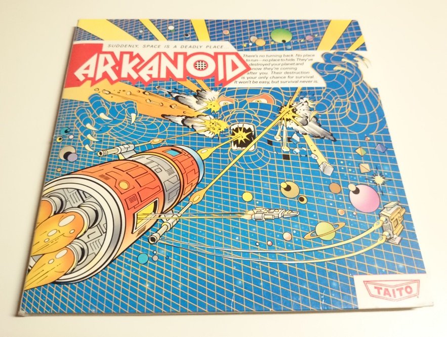 Jaquette du jeu Arkanoid, édition Taito, avec un vaisseau spatial futuriste sur fond bleu