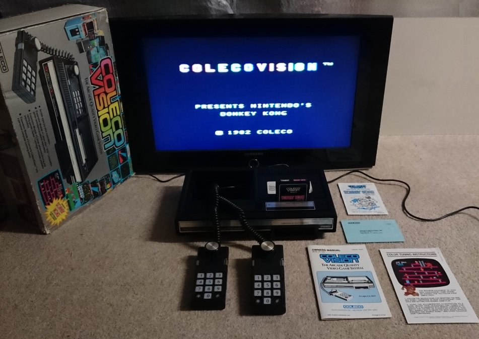 ColecoVision avec écran affichant l'écran-titre du jeu Donkey Kong, manettes et boîte d'origine
