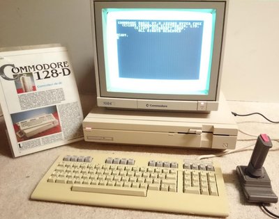 Commodore 128-D avec écran affichant l'invite BASIC, clavier détachable et manette de jeu