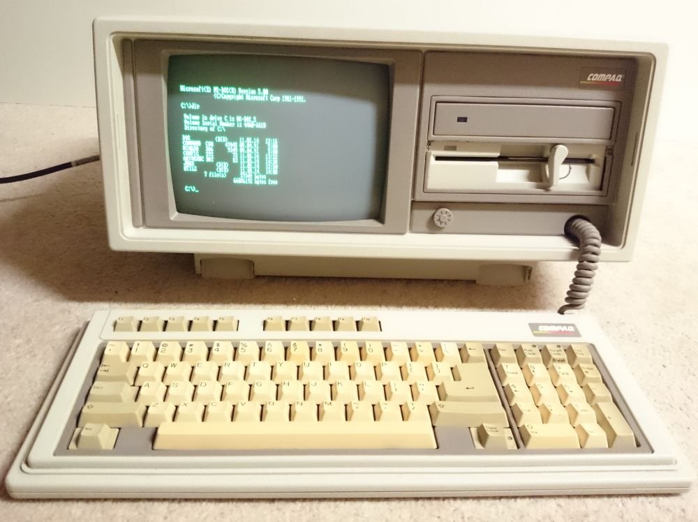 Compaq Portable II ouvert, écran monochrome affichant MS-DOS, clavier détaché posé devant l'unité centrale