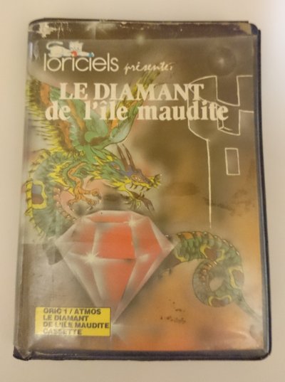 Boîtier cassette du jeu Le diamant de l'île maudite, illustration d'un dragon vert gardant un diamant, édition Loriciel pour Oric