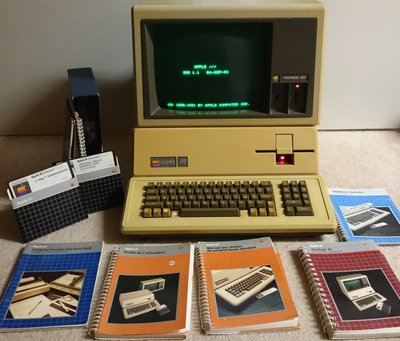 Apple III allumé avec écran SOS 1.1, entouré de ses manuels et disquettes logicielles d'origine