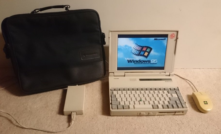 Toshiba T4900CT ouvert avec écran affichant l'écran de démarrage Windows 95, souris et disque dur externe assortis