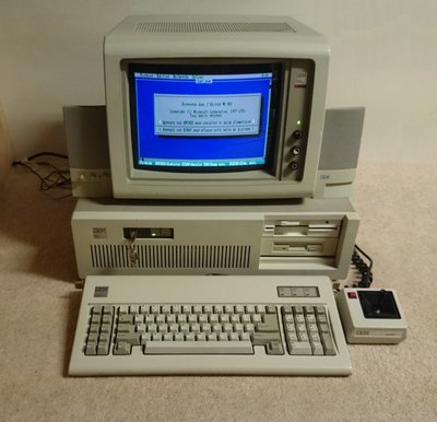 IBM AT 5170 avec écran affichant un menu MS-DOS en français, clavier étendu et manette de jeu IBM