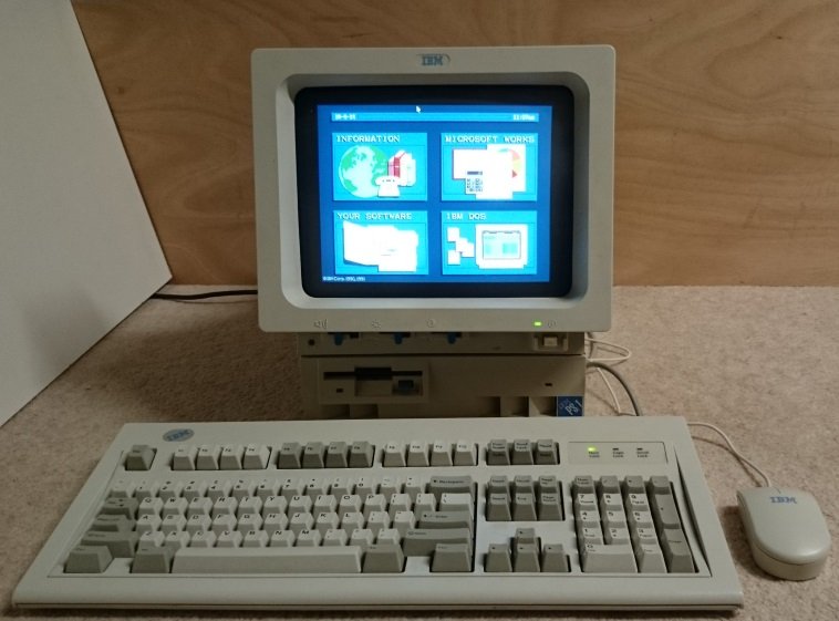 IBM PS/1 avec écran intégré affichant le menu principal, clavier et souris IBM d'origine