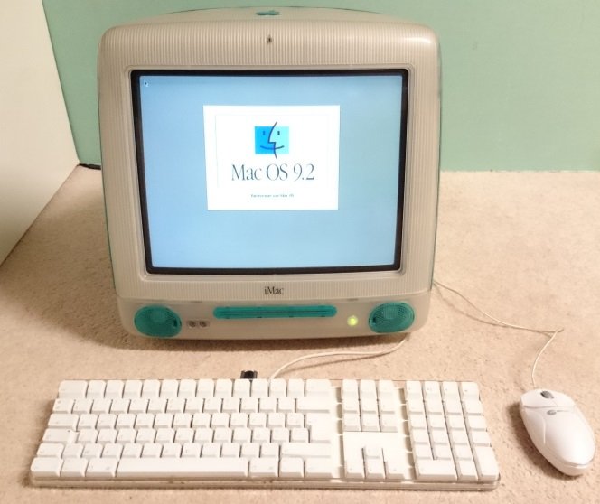 iMac G3 allumé sur l'écran d'accueil Mac OS 9.2, avec clavier et souris d'origine