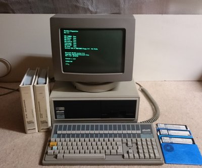 Olivetti M24 sous MS-DOS, écran affichant un diagnostic système, clavier et manuels Olivetti posés devant l'unité centrale