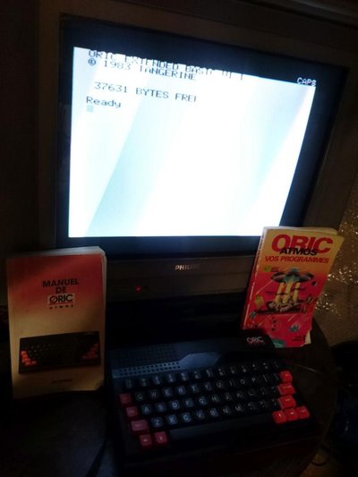 Oric Atmos avec écran affichant l'invite Extended Basic 1.1, manuel et boîte de programmes d'origine