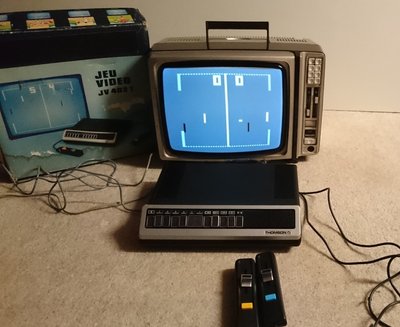 Console Pong Thomson JV 402 T branchée sur un téléviseur, partie en cours avec le score à 0-0, boîte d'origine et manettes visibles