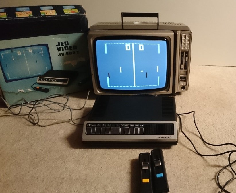 Console Pong Thomson JV 402 T branchée sur un téléviseur, partie en cours avec le score à 0-0, boîte d'origine et manettes visibles