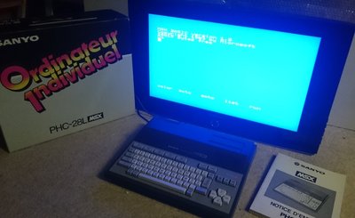 Ordinateur MSX Sanyo PHC-28L avec sa boîte et sa notice, écran affichant l'invite MSX BASIC