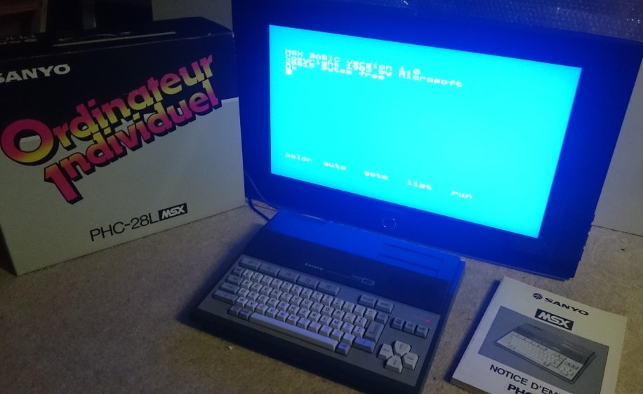 Ordinateur MSX Sanyo PHC-28L avec sa boîte et sa notice, écran affichant l'invite MSX BASIC