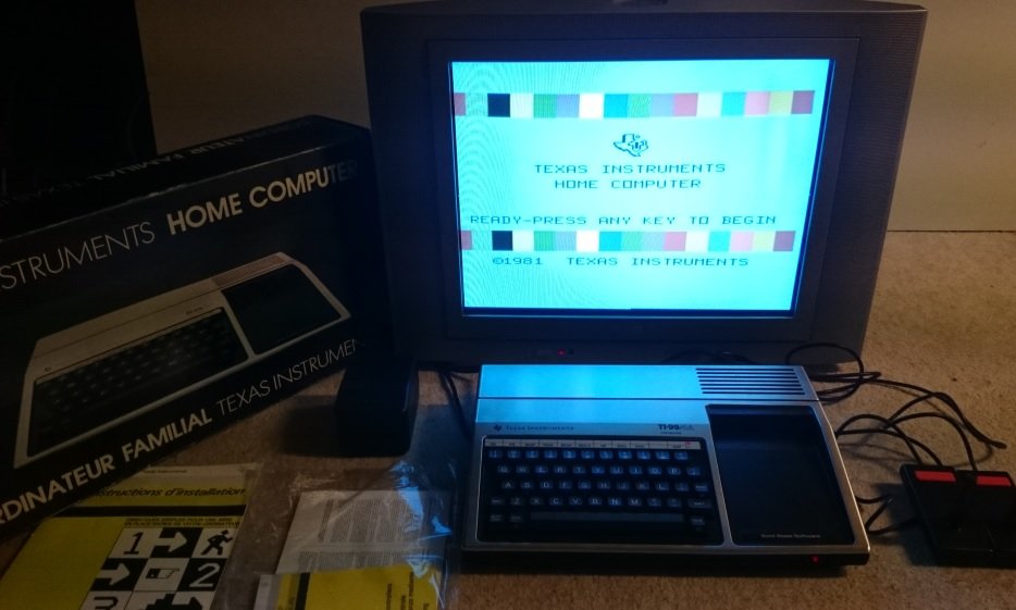 Texas Instruments TI-99/4A allumé, écran de démarrage affichant le logo Texas Instruments, avec boîte et manette
